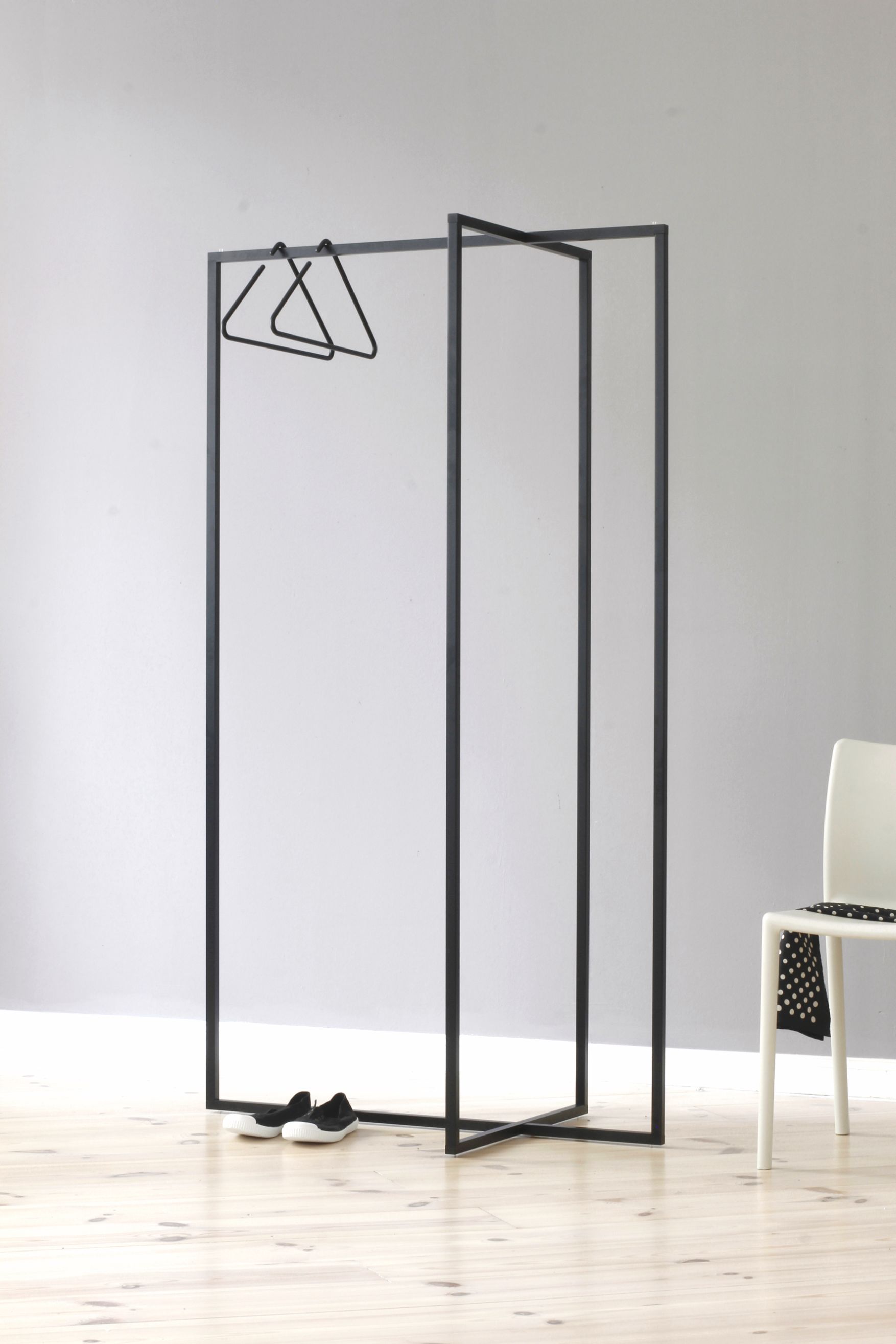 Roomsafari L Garderobe: Schwarzer, minimalistischer Kleiderständer mit Kleiderbügeln und Schuhen im Flur.