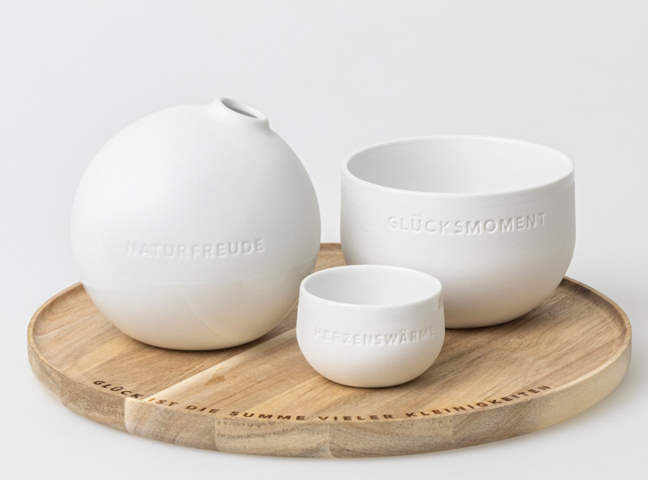 Tablett der kleinen Dinge mit weißer Keramikvase, Schale und Becher auf Holztablett. Dekoration mit Botschaften.