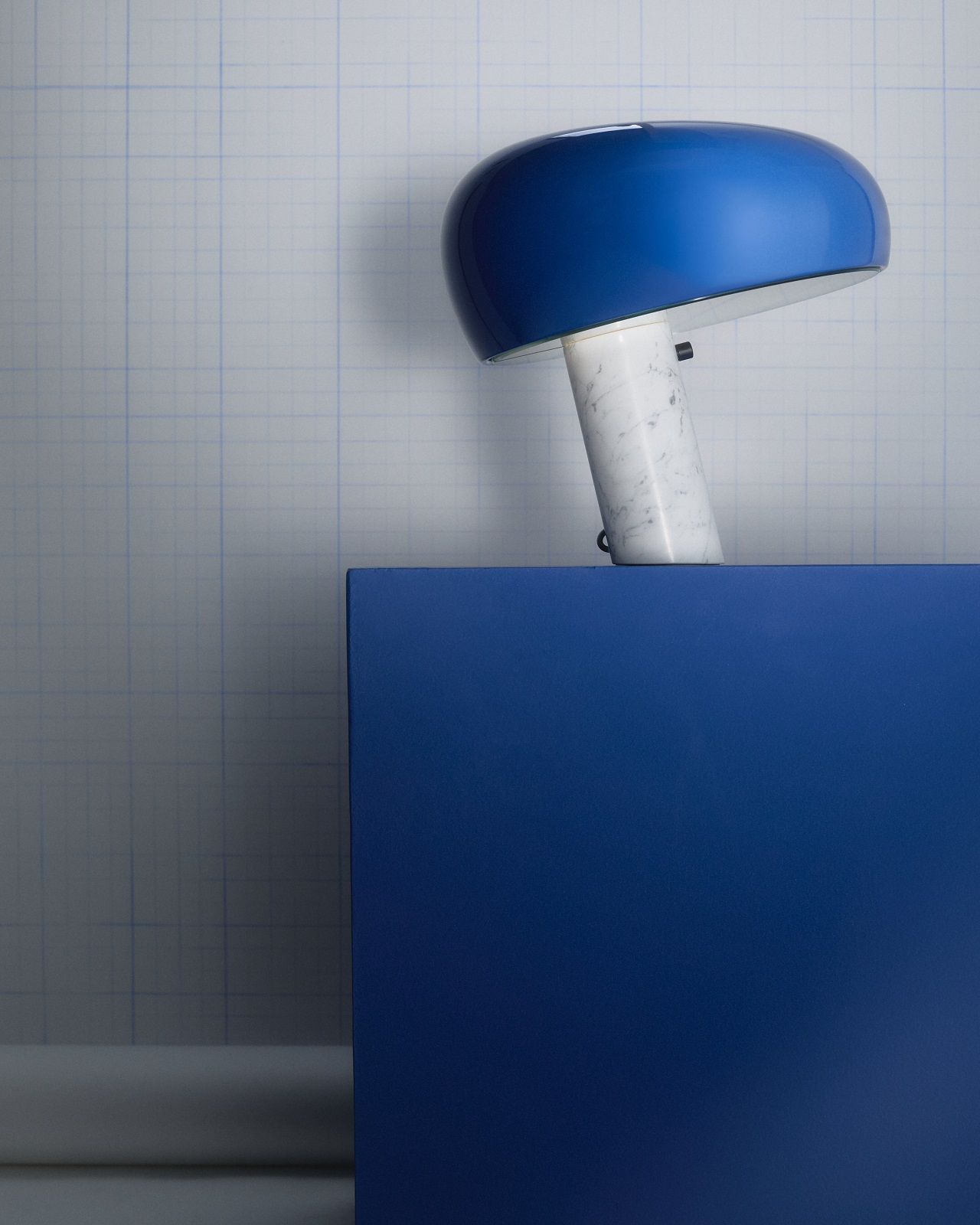 Blaue Snoopy Tischleuchte von Flos mit Marmorfuß auf blauem Sockel. Designlampe für Wohnzimmer.