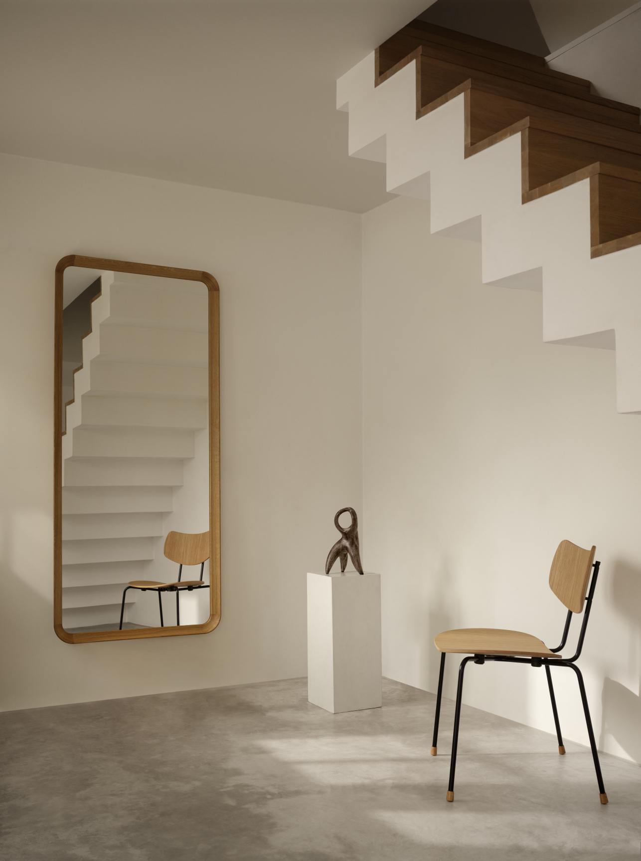 VLA62 Radio House Mirror von Carl Hansen & Søn in minimalistischem Interieur mit Treppe und Stuhl.