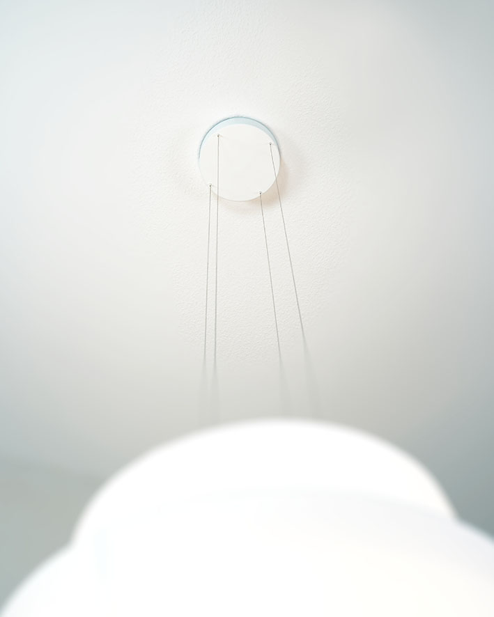 Detailaufnahme der weißen Fly Pendelleuchte von Maigrau, Deckenbefestigung mit filigranen Stahlseilen.