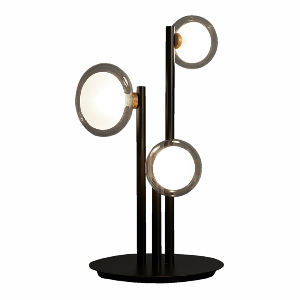 Nabila Tischleuchte von Tooy mit drei leuchtenden Glaskugeln auf schwarzem Metallgestell.