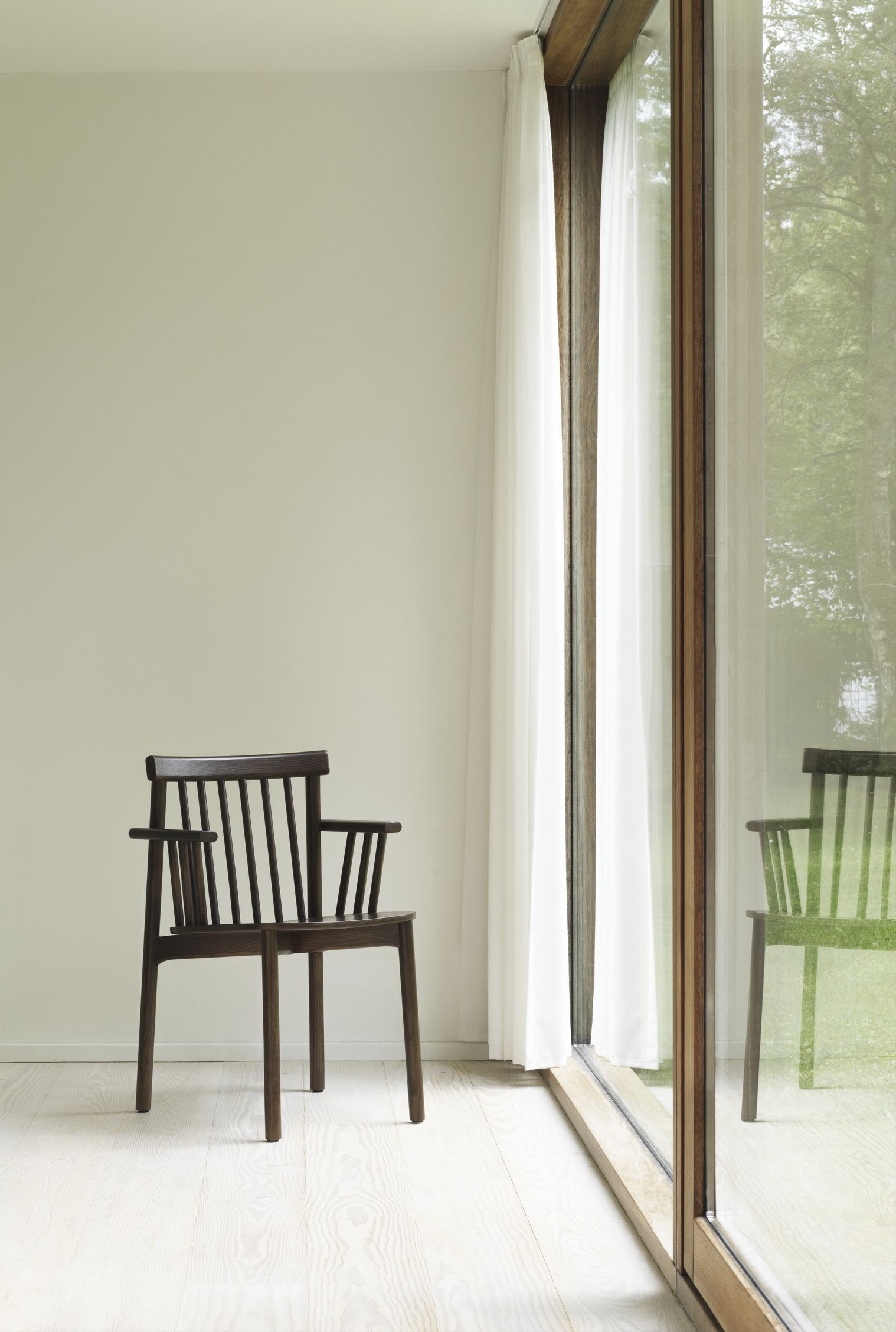 Dunkelbrauner Pind Armchair Armlehnenstuhl von Normann Copenhagen vor Fenster mit Vorhang. Design Stuhl für Wohnzimmer.