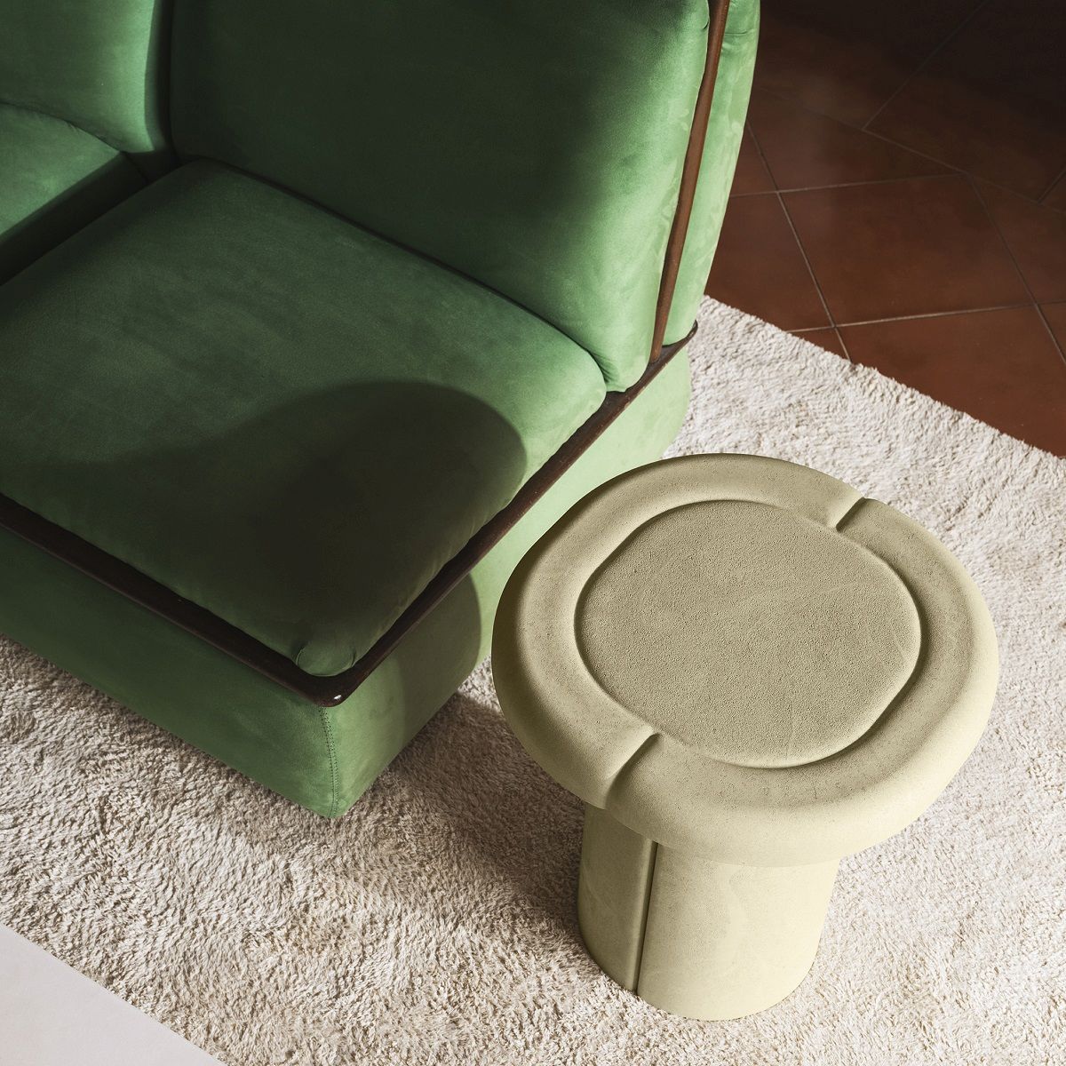 Nahaufnahme des beigen Alder Side Table Beistelltisches von Mater neben einem grünen Sofa.