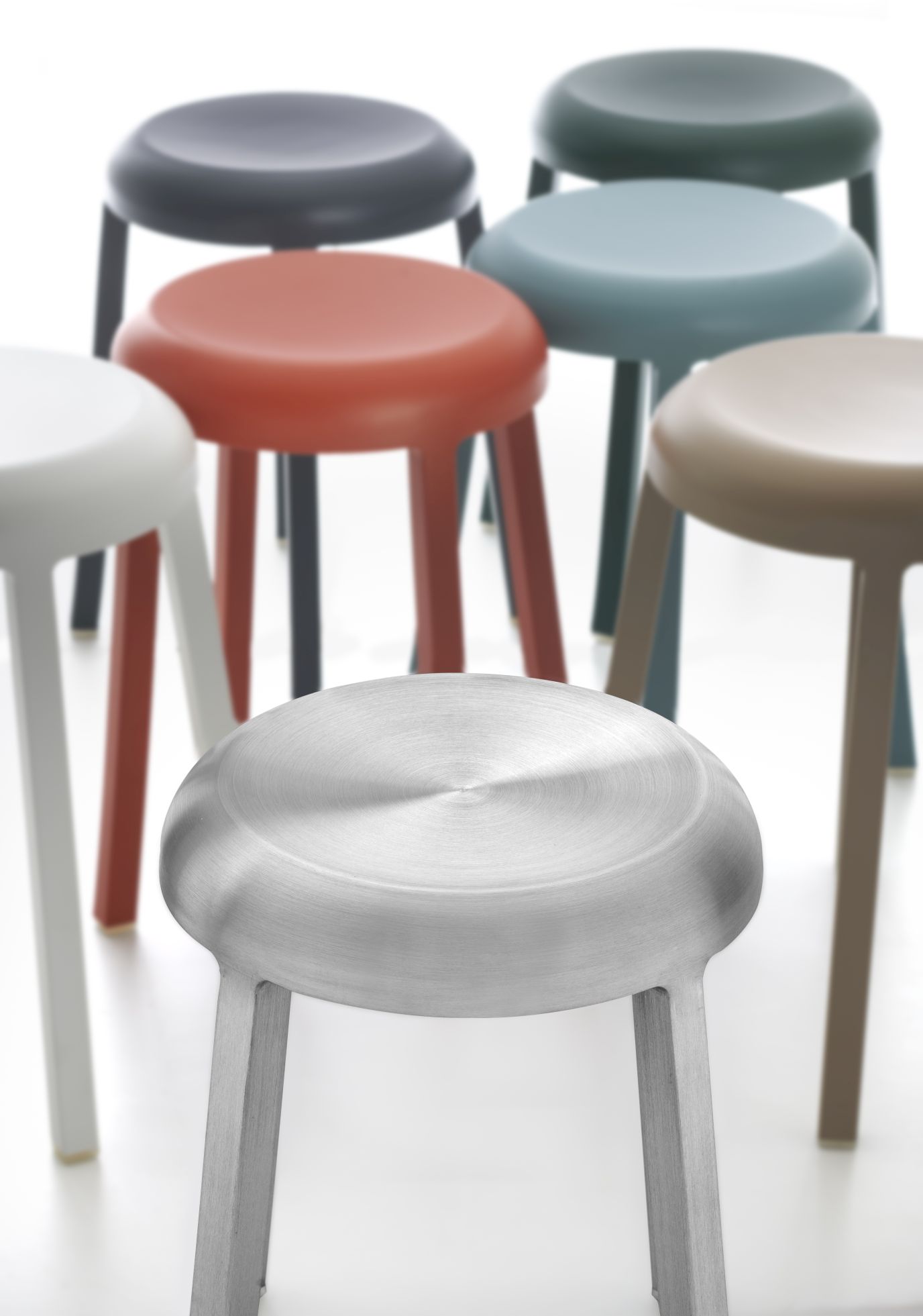 Nahaufnahme des polierten Aluminium Za Stool Hockers von Emeco, umgeben von farbigen Hockern.