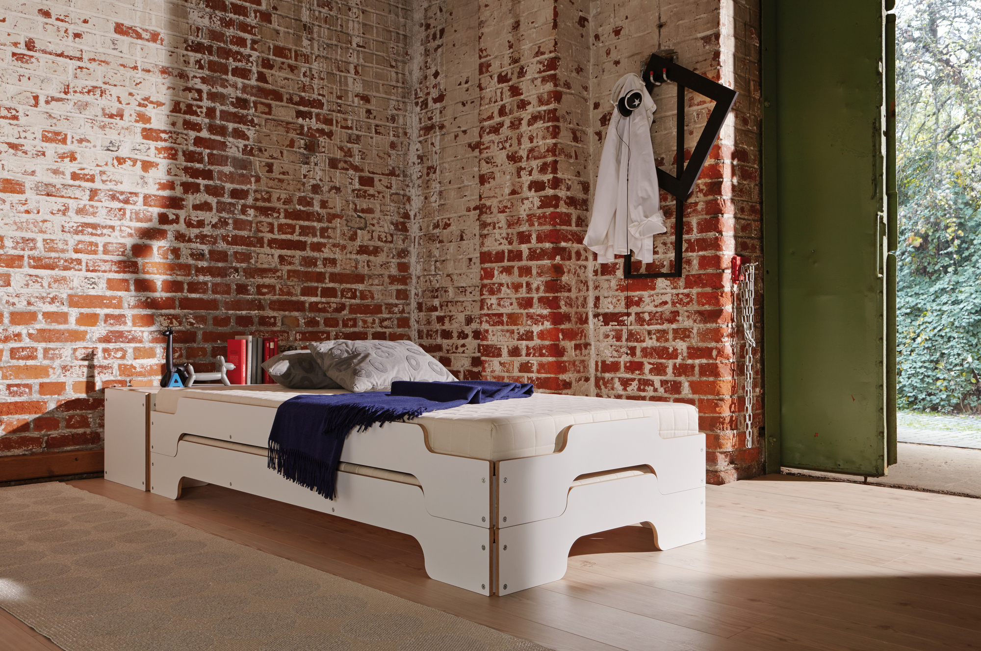 Weißes Stapelbett mit Roll-Lattenrost von Müller Möbelwerkstätten, Größe 190x140 cm, vor Backsteinwand.