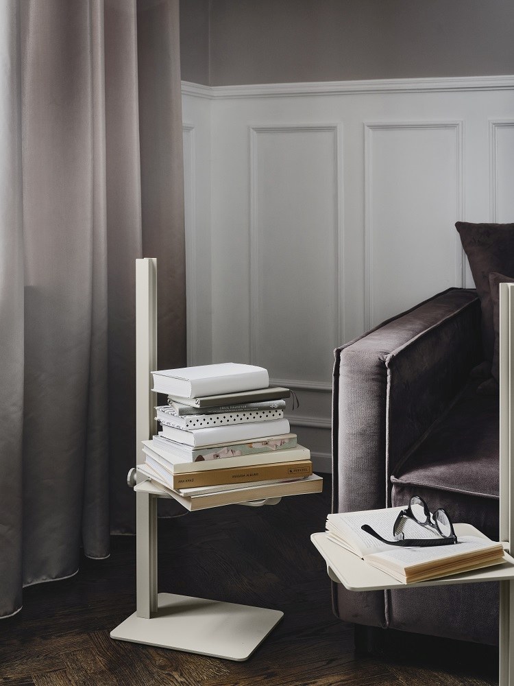 Beiger Museum Sidetable Beistelltisch von String Furniture mit Büchern, höhenverstellbar, neben einem Sofa.