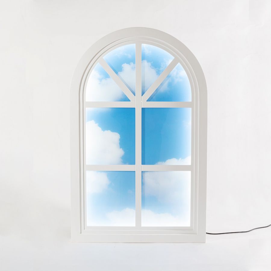 Weiße Grenier Window Leuchte von Seletti mit blauem Himmel und Wolken im Fenster.