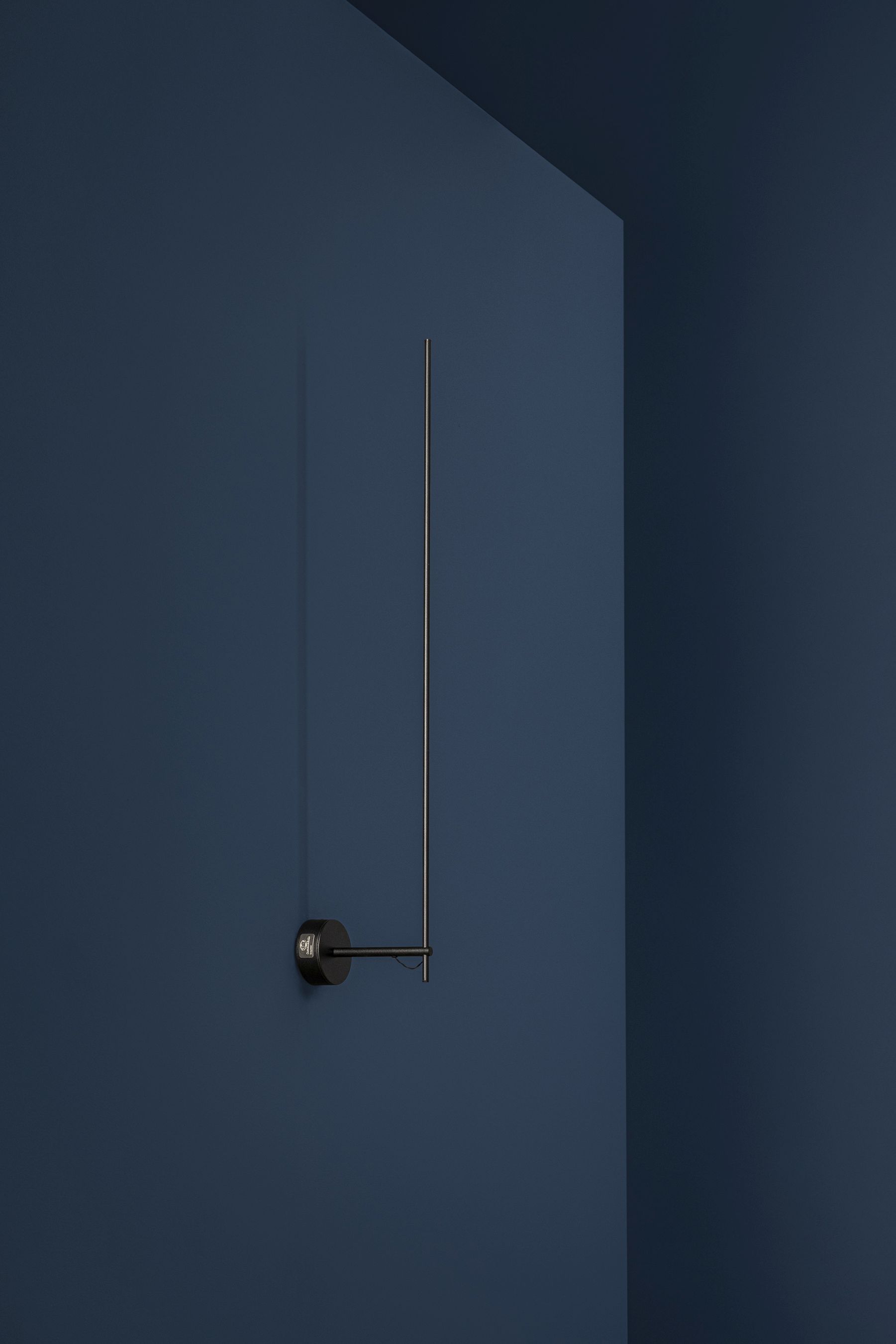 Schlichte Light Stick Wandleuchte von Catellani & Smith an blauer Wand. Moderne Innenbeleuchtung.