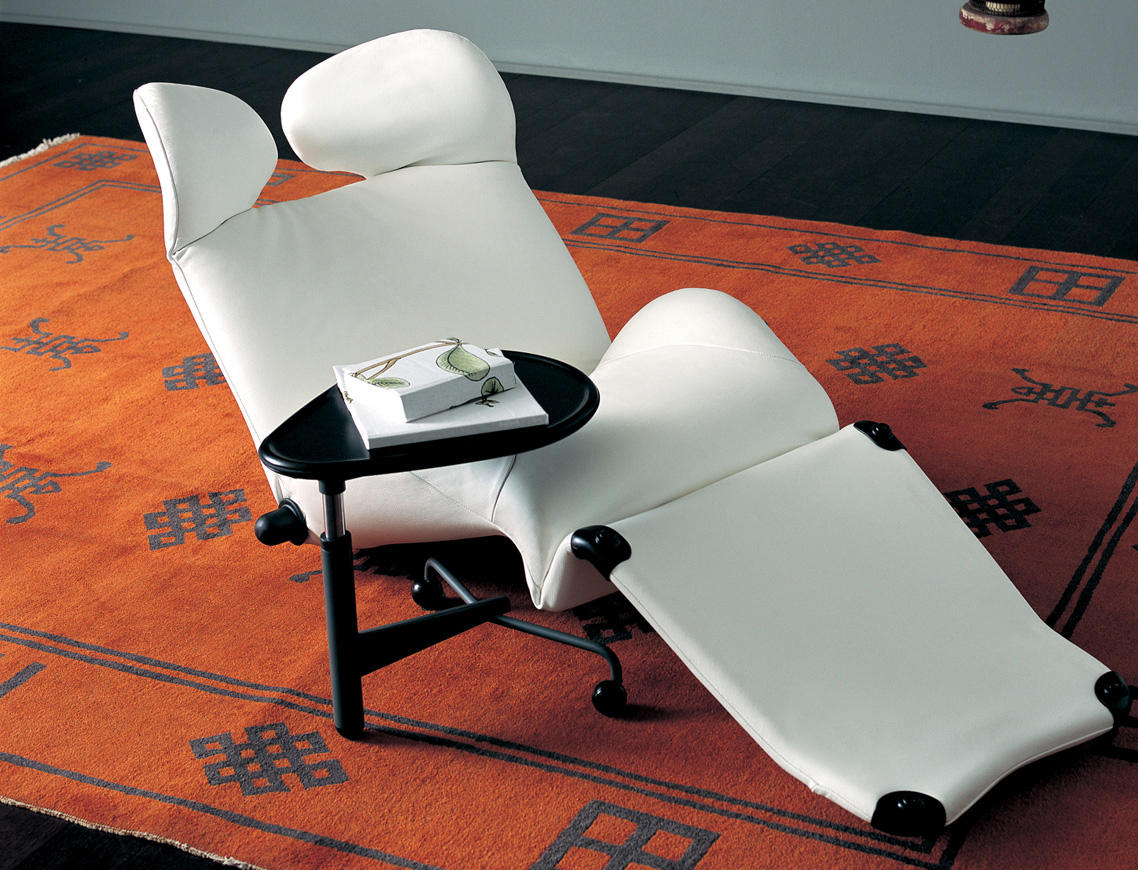 Weißer Cassina Wink Sessel mit Fußhocker und Beistelltisch auf einem gemusterten Teppich.