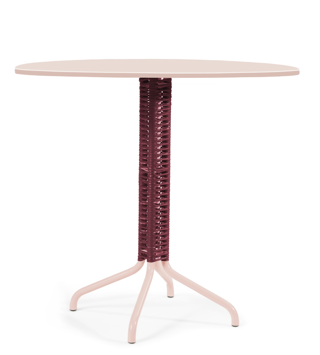 Cielo Table Outdoor Tisch in Pink Sand mit rotem, geflochtenem Bein.