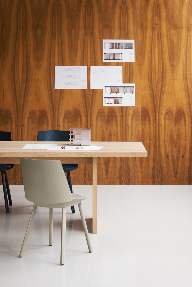 TA24 Ashida Tisch von e15: Rechteckiger Esstisch aus Massivholz mit Stühlen und Büroaccessoires.