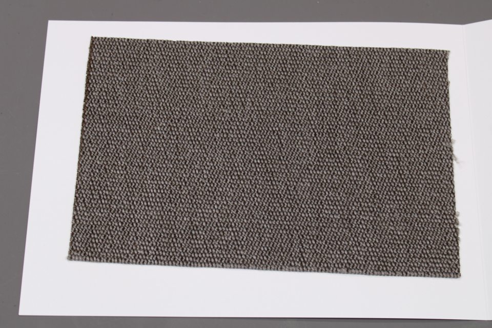 Stoffmusterkarte Gruppe 91 Cor: Nahaufnahme eines grauen, texturierten Möbelstoffes auf weißem Karton.