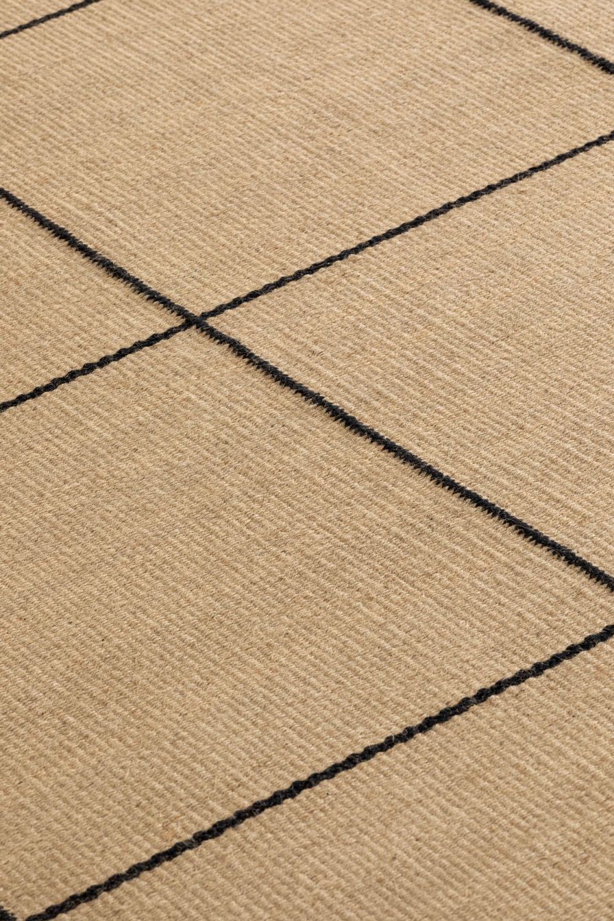 Detailaufnahme des Roots Teppichs von Gan, beige mit schwarzem Linienmuster, hochwertiger Teppich für Wohnräume.