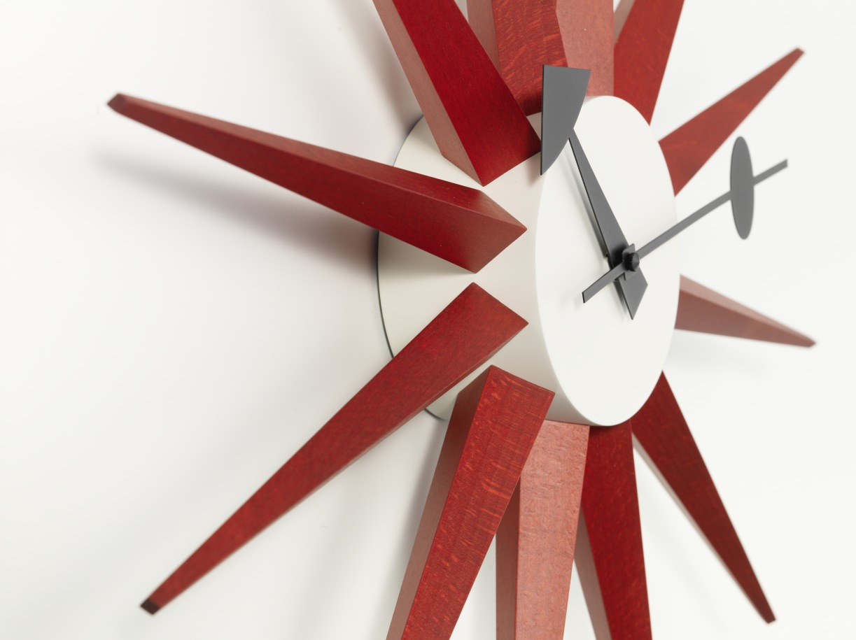 Detailaufnahme der roten Sunburst Clock Wanduhr von Vitra mit Holzstrahlen und weißem Ziffernblatt.