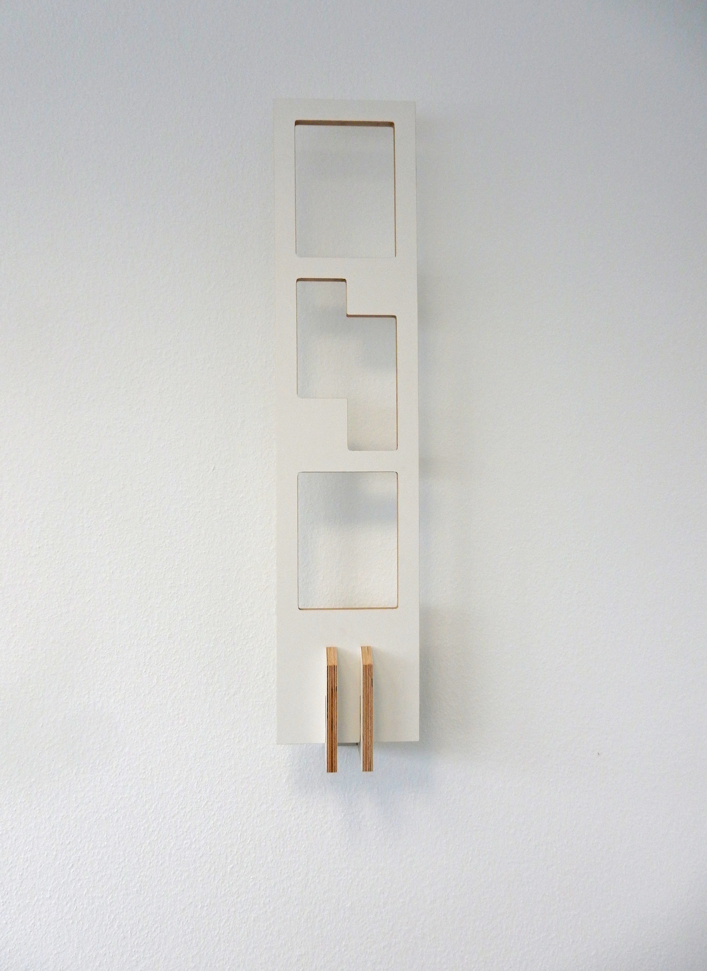 Weißes Tojo Lesestoff Bücherregal an der Wand mit drei Fächern und Holzdetails.