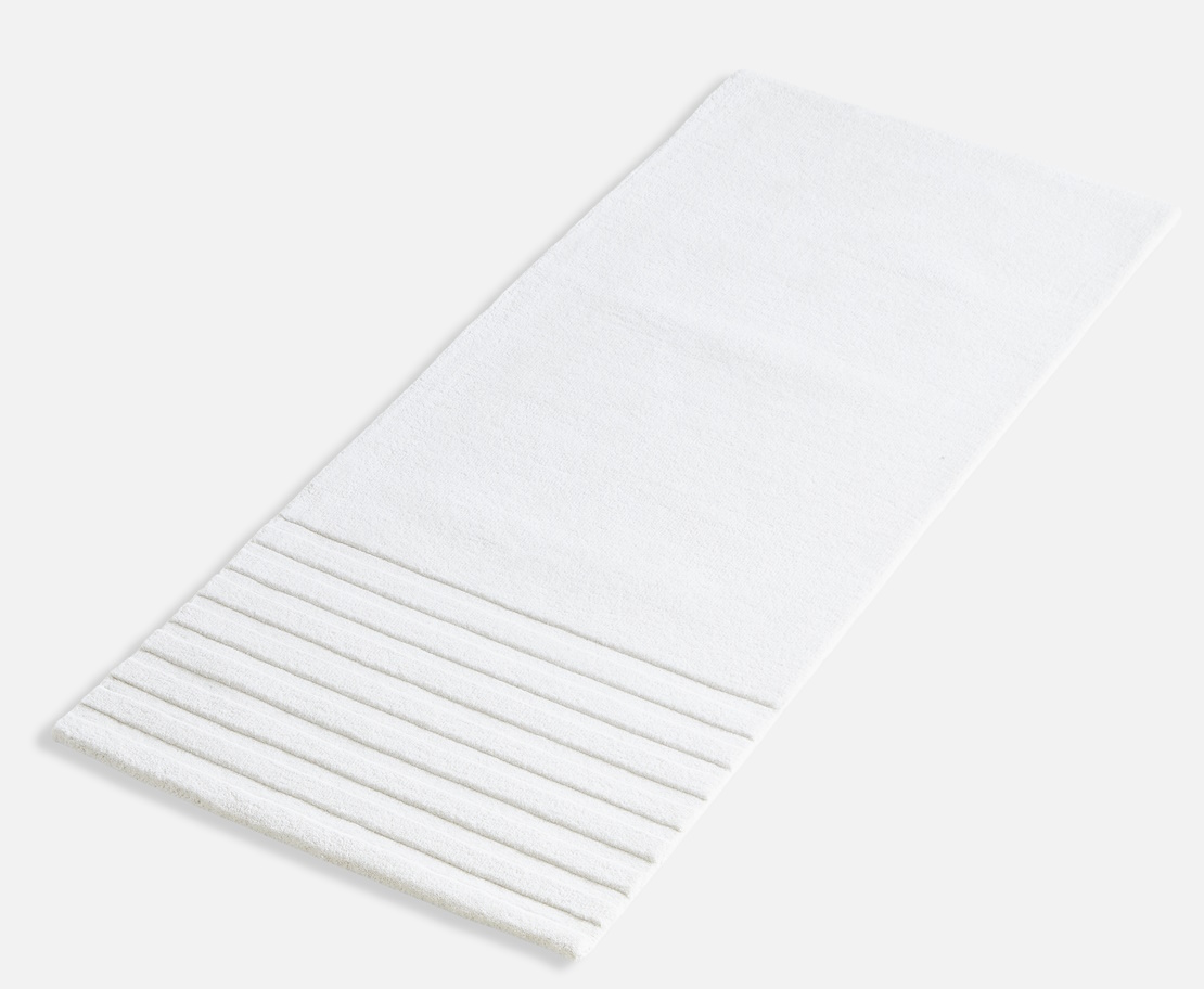 Weißer Kyoto Teppich von Woud (80x200 cm) mit gerippter Textur im unteren Bereich.