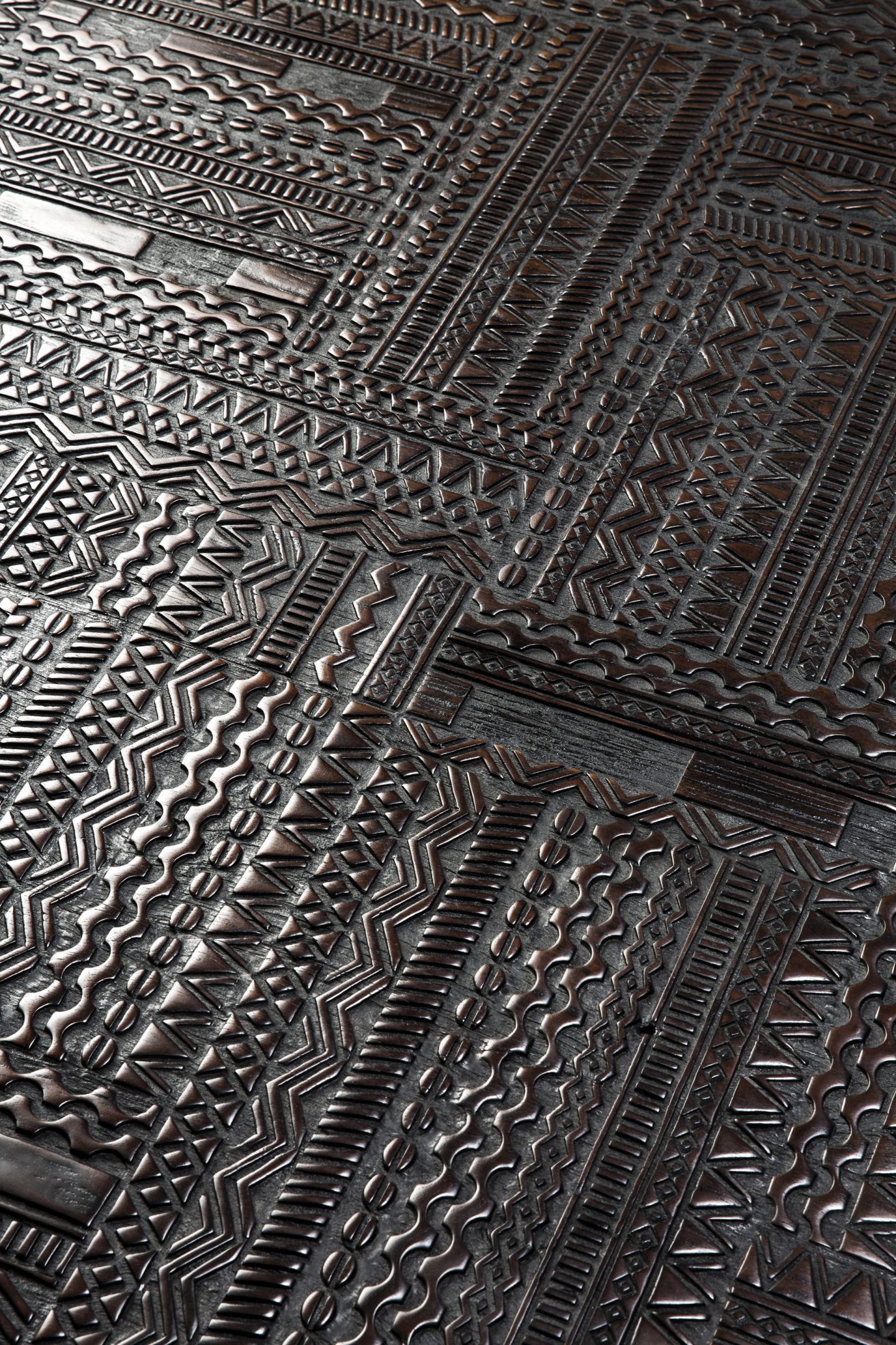 Detailaufnahme der schwarzen Teakholz-Oberfläche des Tabwa Couchtisches von Ethnicraft mit ethnischen Mustern.