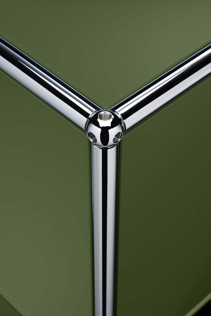 Detailaufnahme USM Haller Möbelbausystem: Olivgrüne Einschubtür und verchromtes Verbindungsrohr als Ersatzteil.