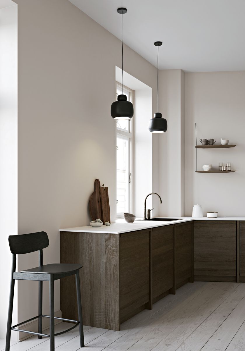 Zwei schwarze Stone Pendelleuchten von Woud über einer modernen Küche mit dunklen Holzfronten.