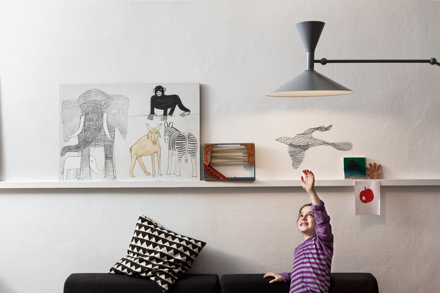 Mädchen versucht, die Birds Vogel Hängedeko von Magis an der Wand zu berühren.