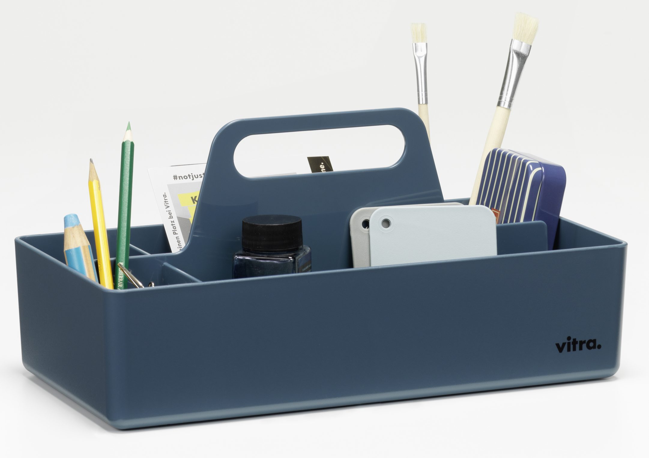 Vitra Toolbox RE, meerblaue Aufbewahrungsbox mit Griff und diversen Büro- und Malutensilien, ideal zur Organisation.