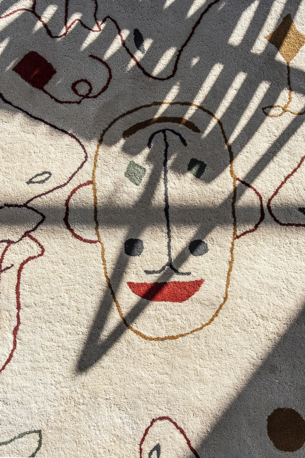 Detailaufnahme: Nanimarquina Silhouette Teppich, runder Tufting Teppich mit abstraktem Gesichtsmuster und Schatten.