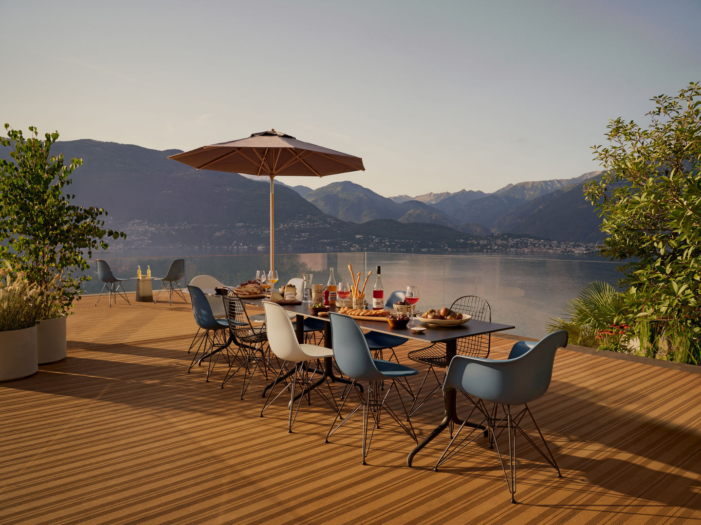 Esstisch mit mehreren Eames Plastic Armchairs DAR Stühlen von Vitra auf einer Terrasse.