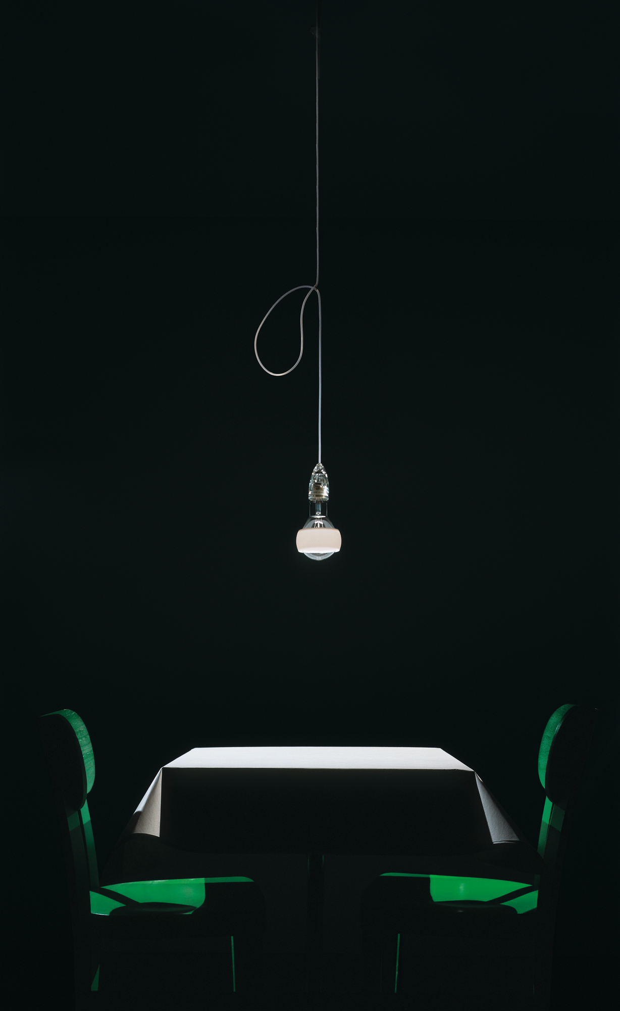 Johnny B. Good Lampe von Ingo Maurer über Esstisch mit grünen Stühlen.