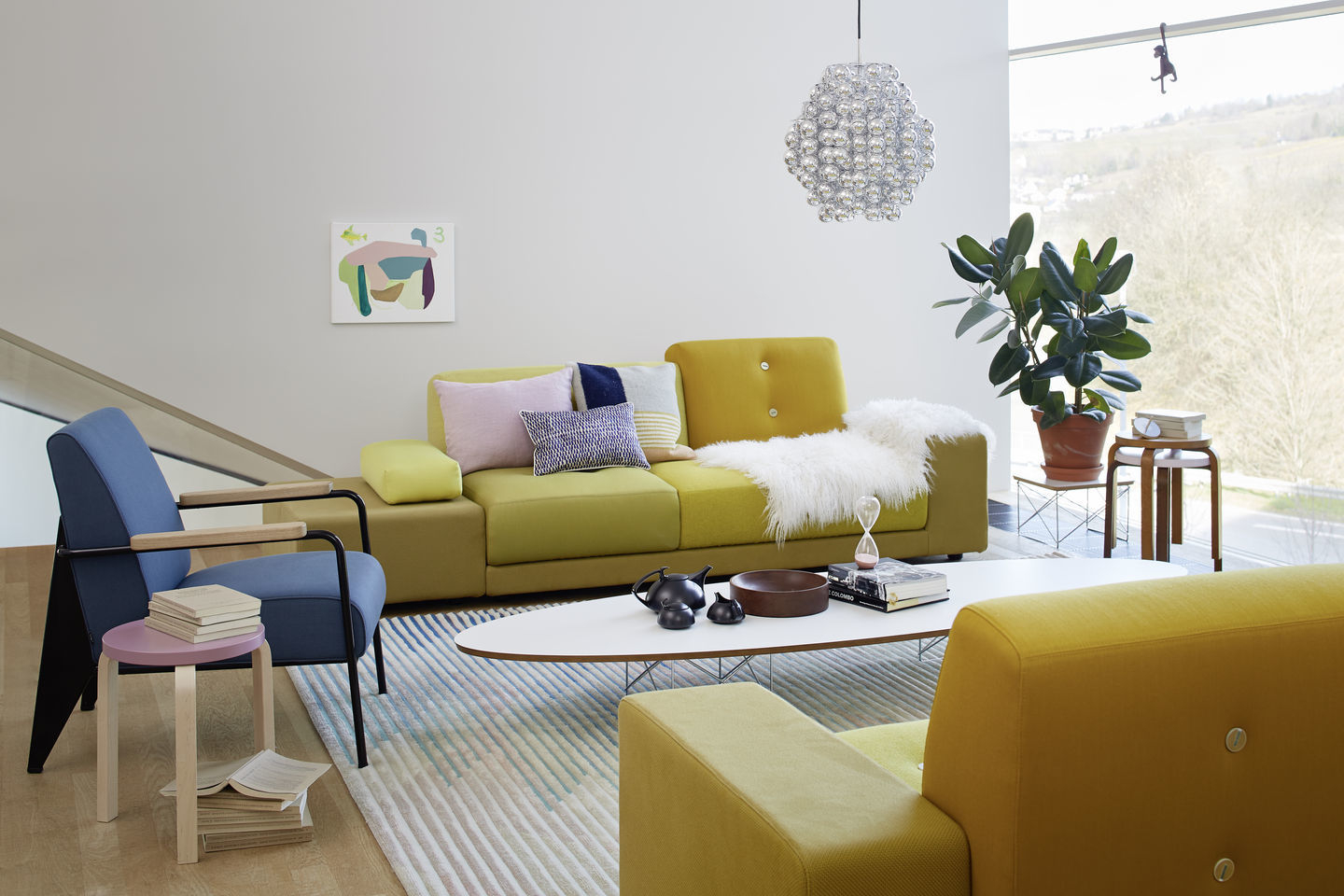 Wohnzimmer mit blauem Vitra Sessel und gelb-grünem Sofa, moderne Möbel und Dekoration.