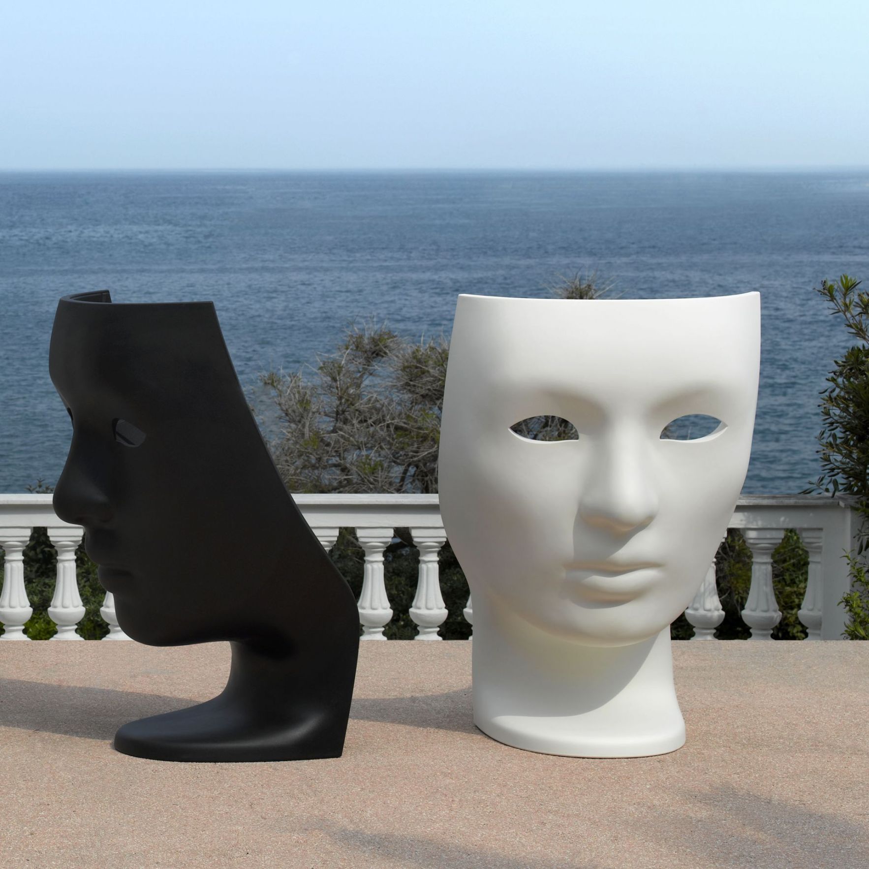 Schwarzer und weißer Masken-Hocker im Freien mit Meerblick. Moderne Designermöbel für Garten und Terrasse.