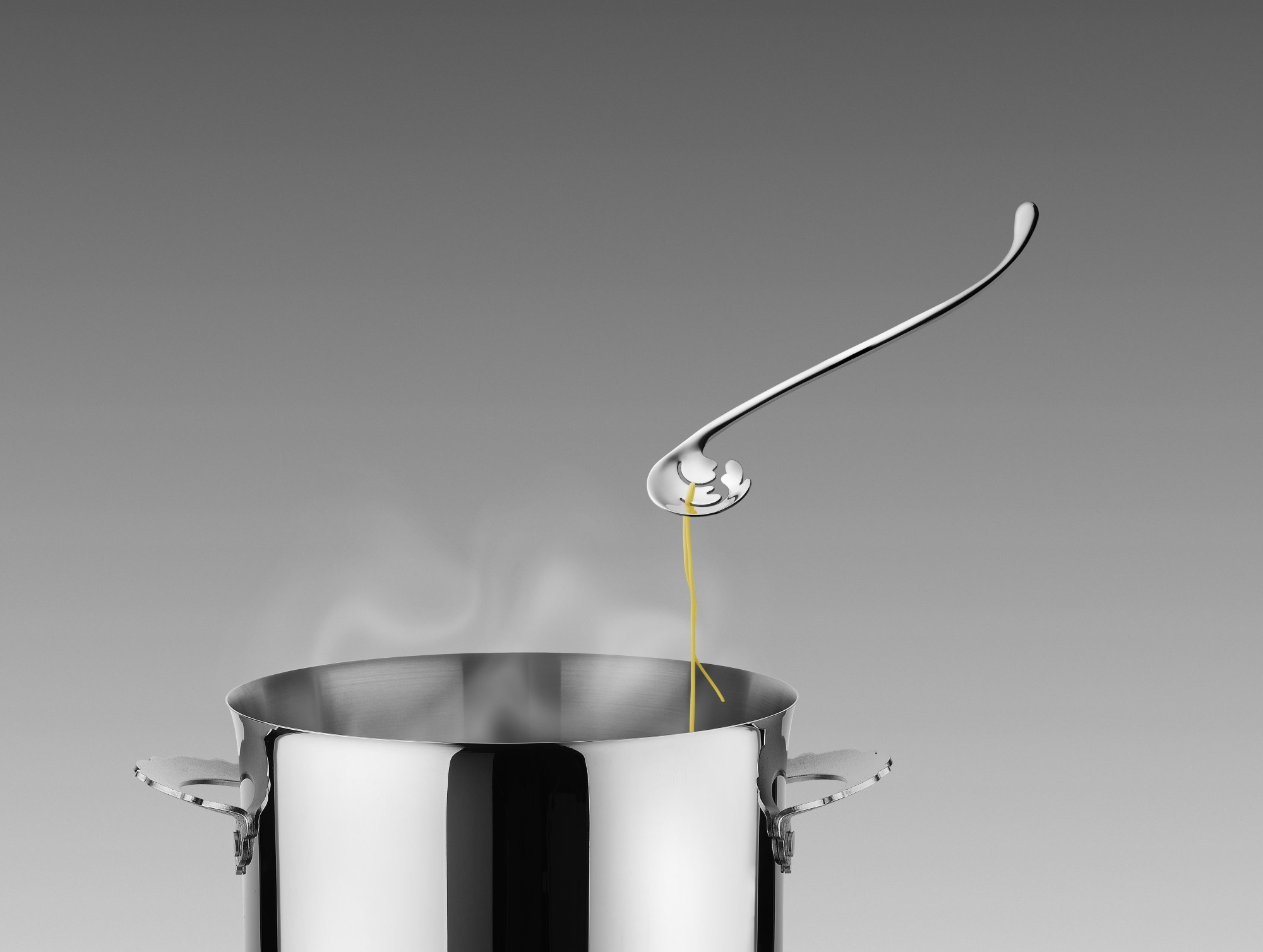 Alessi Pastatester MMI31 in Aktion: Spaghetti werden aus einem dampfenden Topf gehoben.