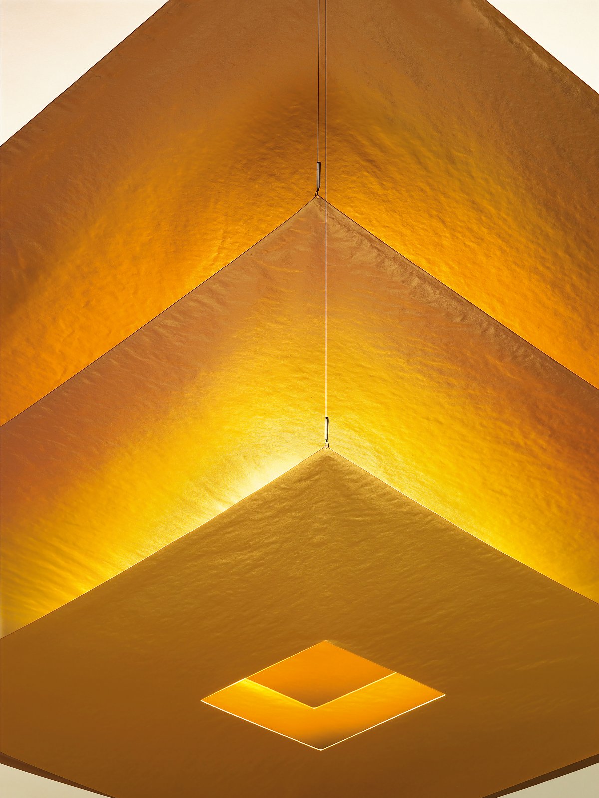 Detailaufnahme der goldenen Lil Luxury Deckenleuchte von Ingo Maurer mit quadratischem Lichtausschnitt.