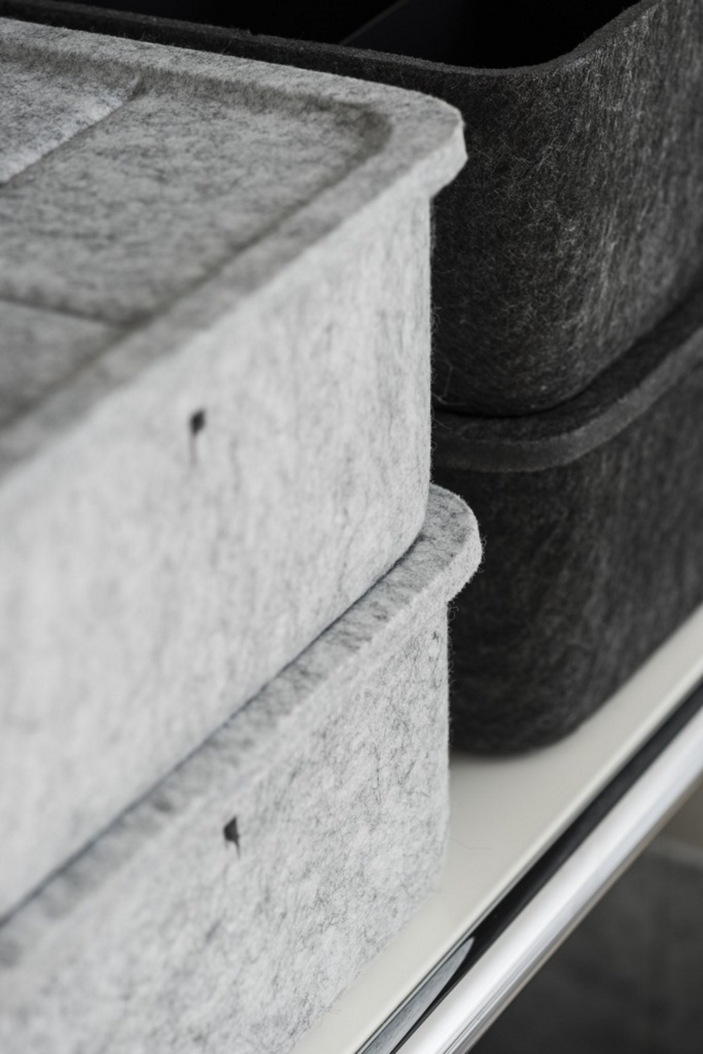 Graue und schwarze USM Haller Inos Box tief aus Filz im Detail auf einem Regal.