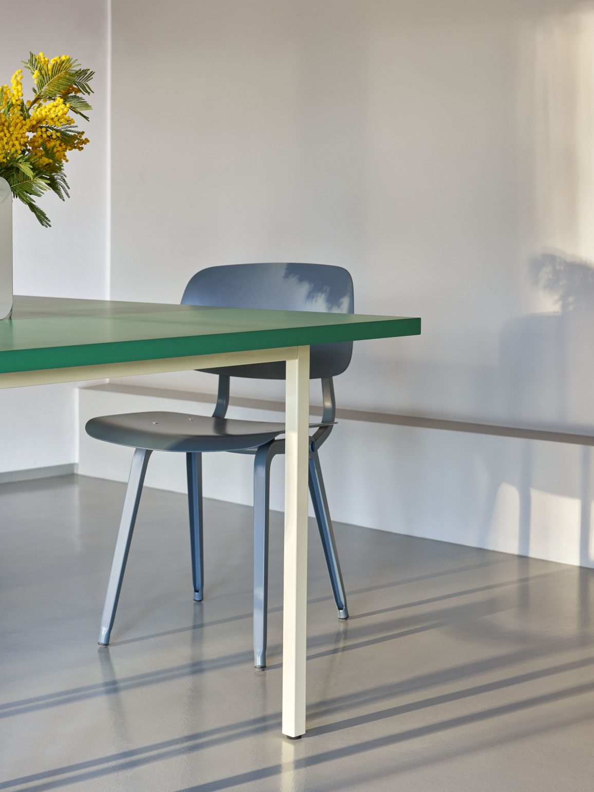 Hay Two Colour Table mit blauem Stuhl und Mimosen-Blumenstrauß, modernes Design für Esszimmer und Büro.