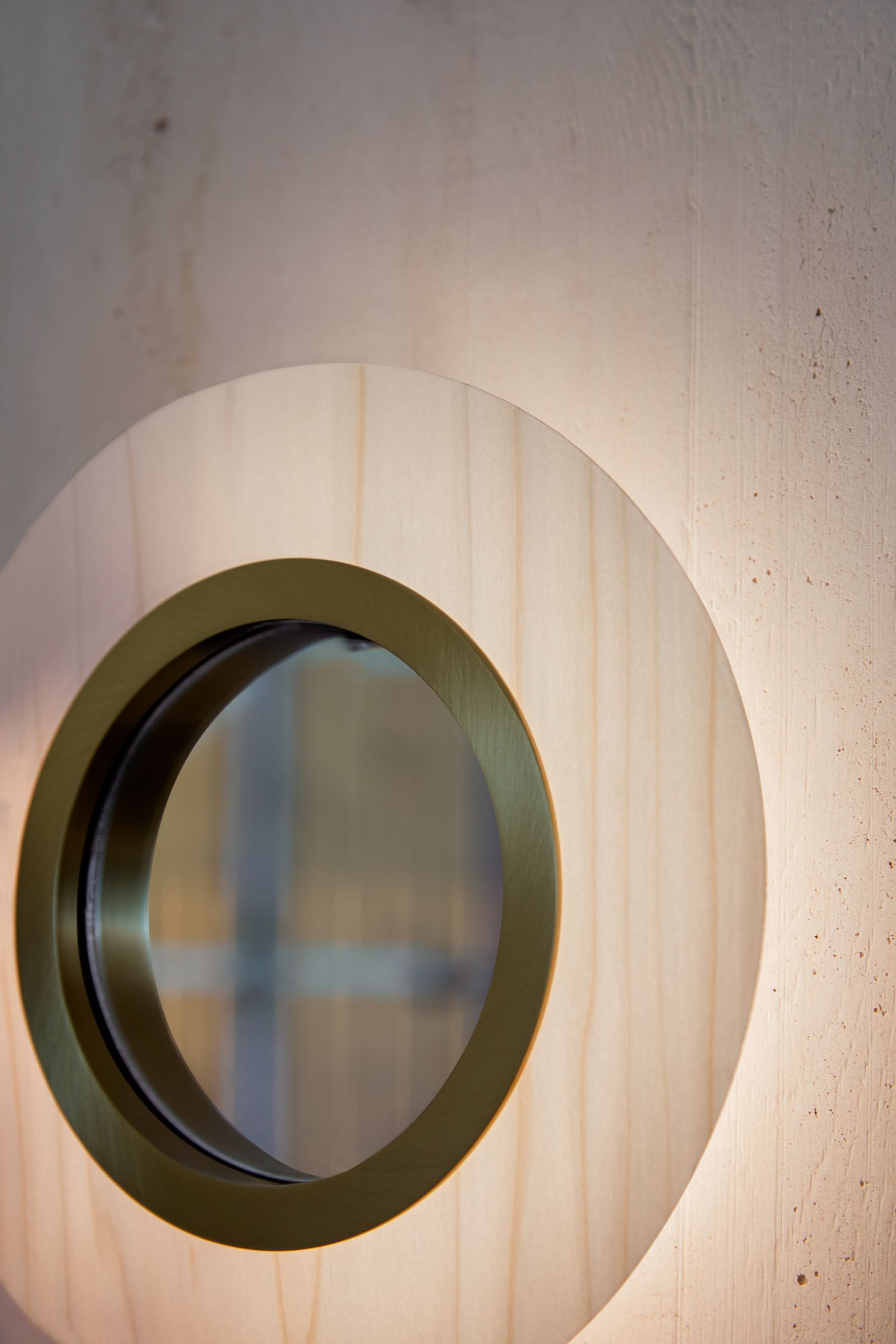 Lens LED Wandleuchte von LZF Lamps: Runde, elfenbeinweiße Holzleuchte mit hellrosa Akzenten und Metallring.