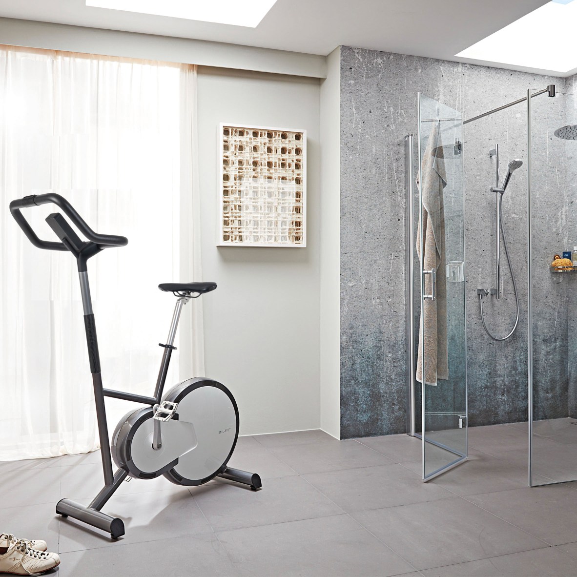 Grauer Heimtrainer im Badezimmer mit Dusche und Kunstwerk, ideal für Fitness zu Hause.