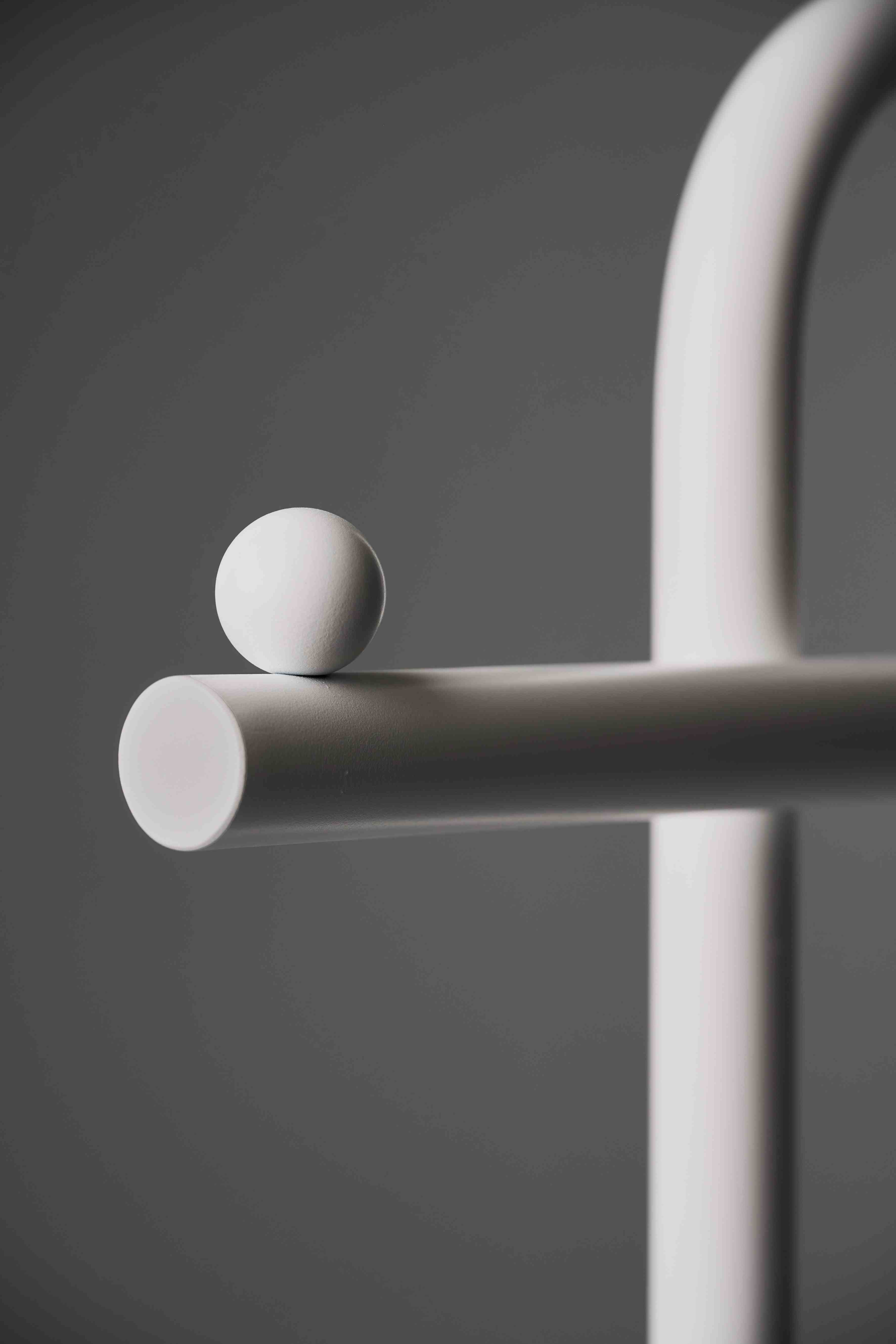 Detailaufnahme des Schönbuch Slinga Garderobenständers in Weiß mit einer Kugel. Modernes Design für Flur und Diele.