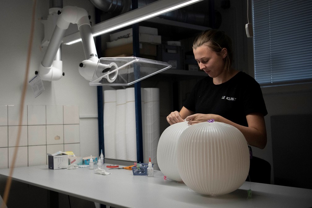 Frau fertigt Le Klint Lamella Pendelleuchte. Elegante Designerlampe, skandinavisches Design für Wohnraum und Beleuchtung.