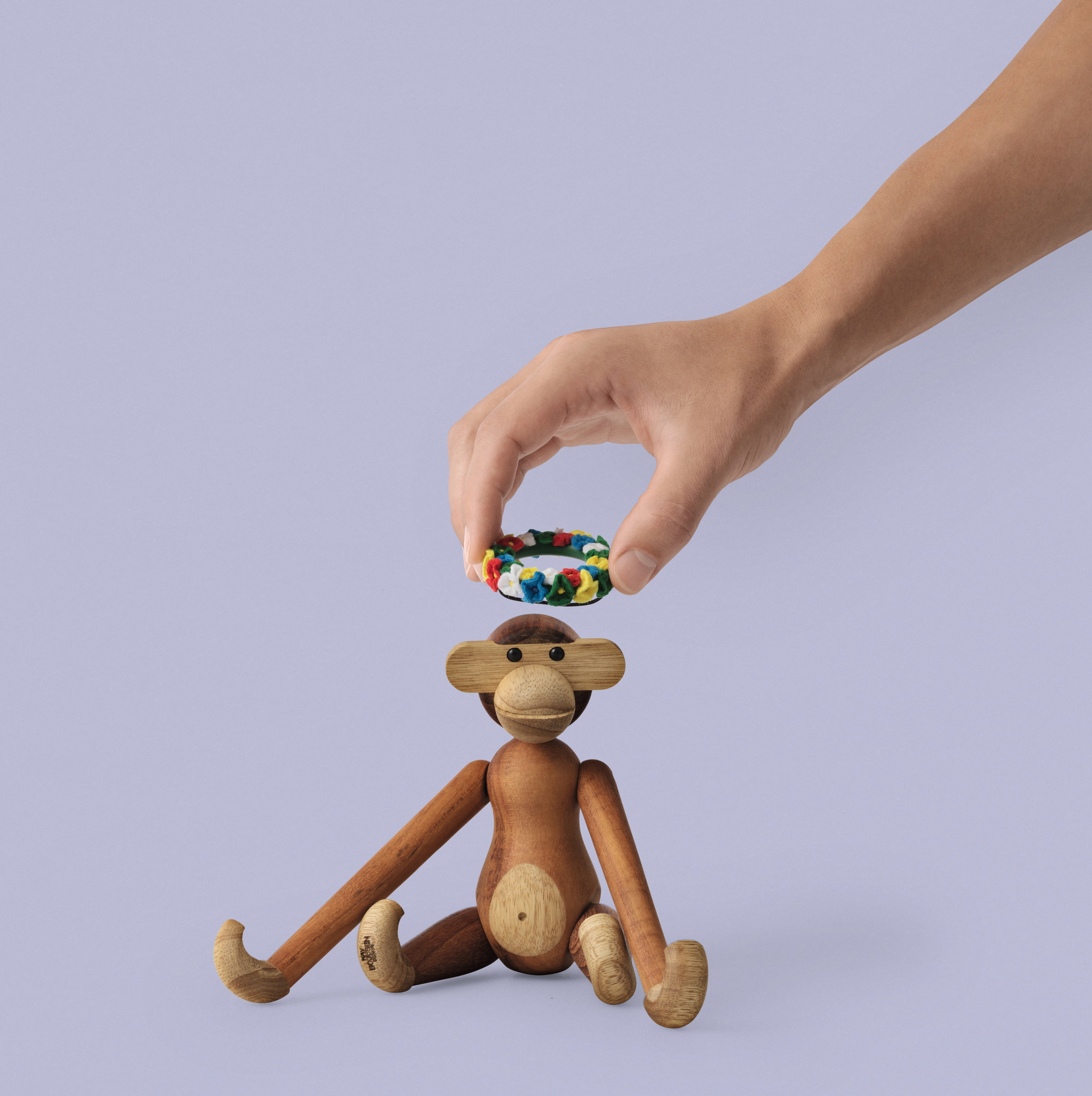 Hand hält Mittsommer Kranz über Kay Bojesen Affe Holzfigur. Dekoration für Holztiere.