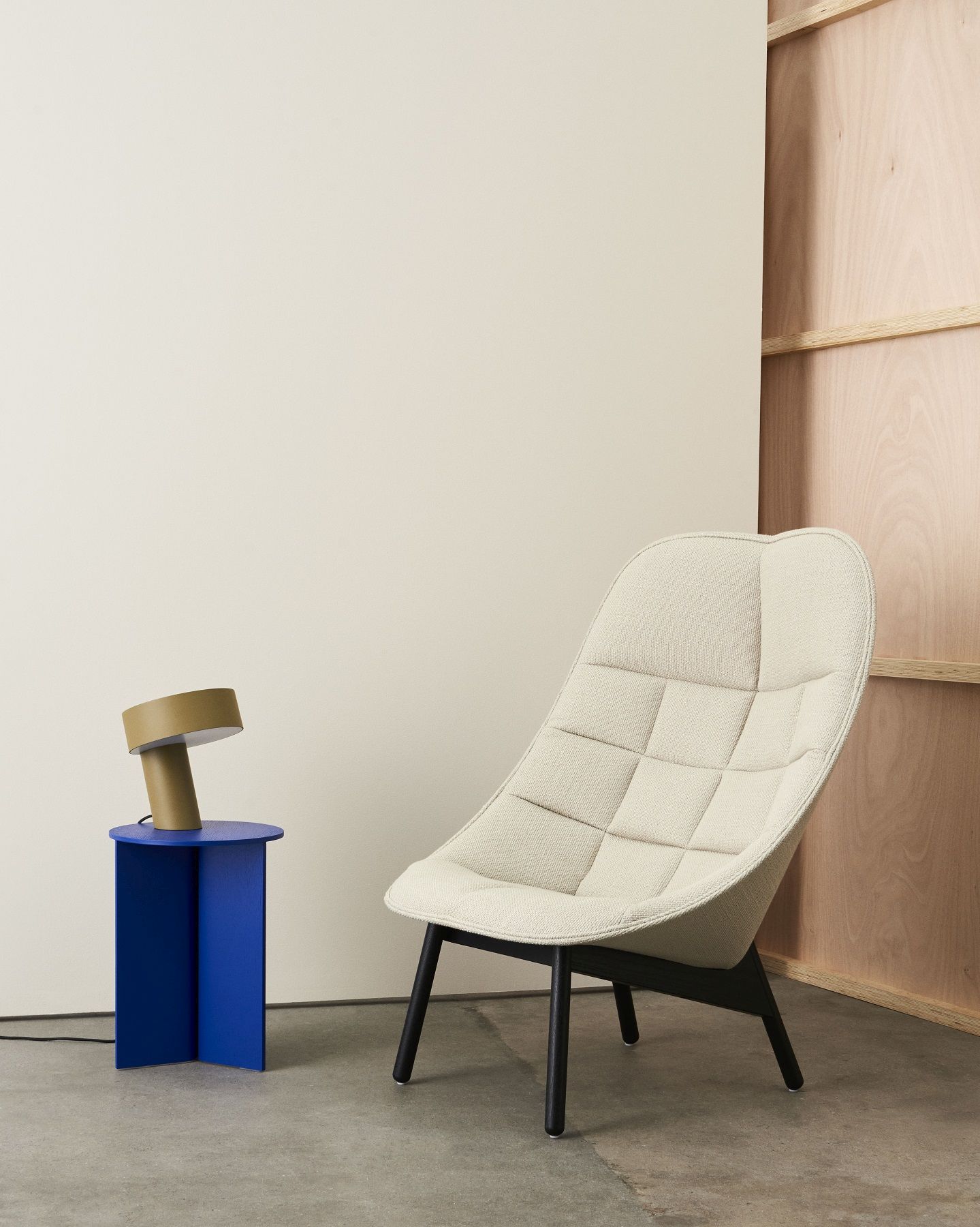 Blauer Hay Slit Table Beistelltisch neben einem Sessel mit einer Lampe darauf.