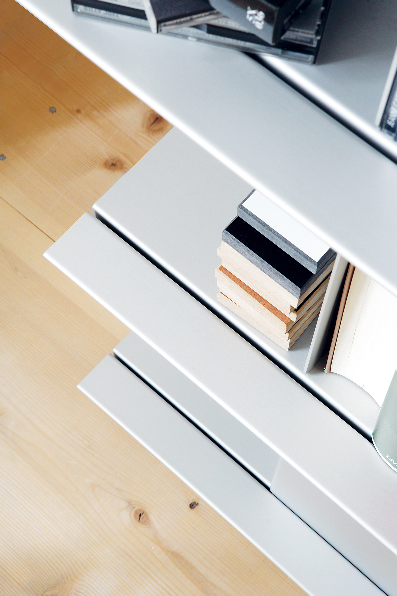 Detailaufnahme des Zoll D Regals von Nils Holger Moormann mit Büchern und hellen Holzfußboden.