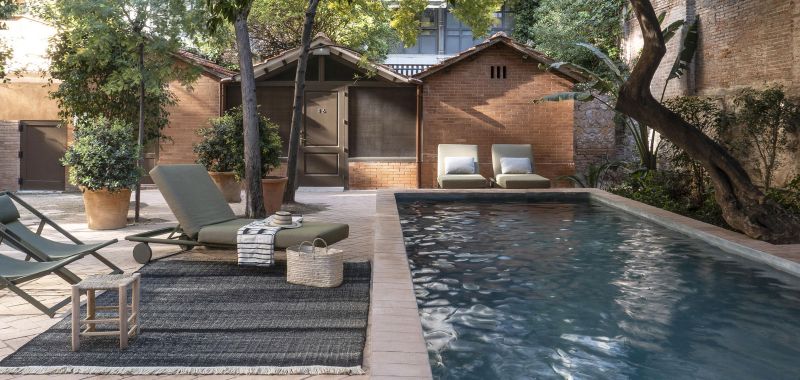 Nanimarquina Tres Outdoor Texture Teppich in Senf neben Pool mit Gartenmöbeln und Dekoration.