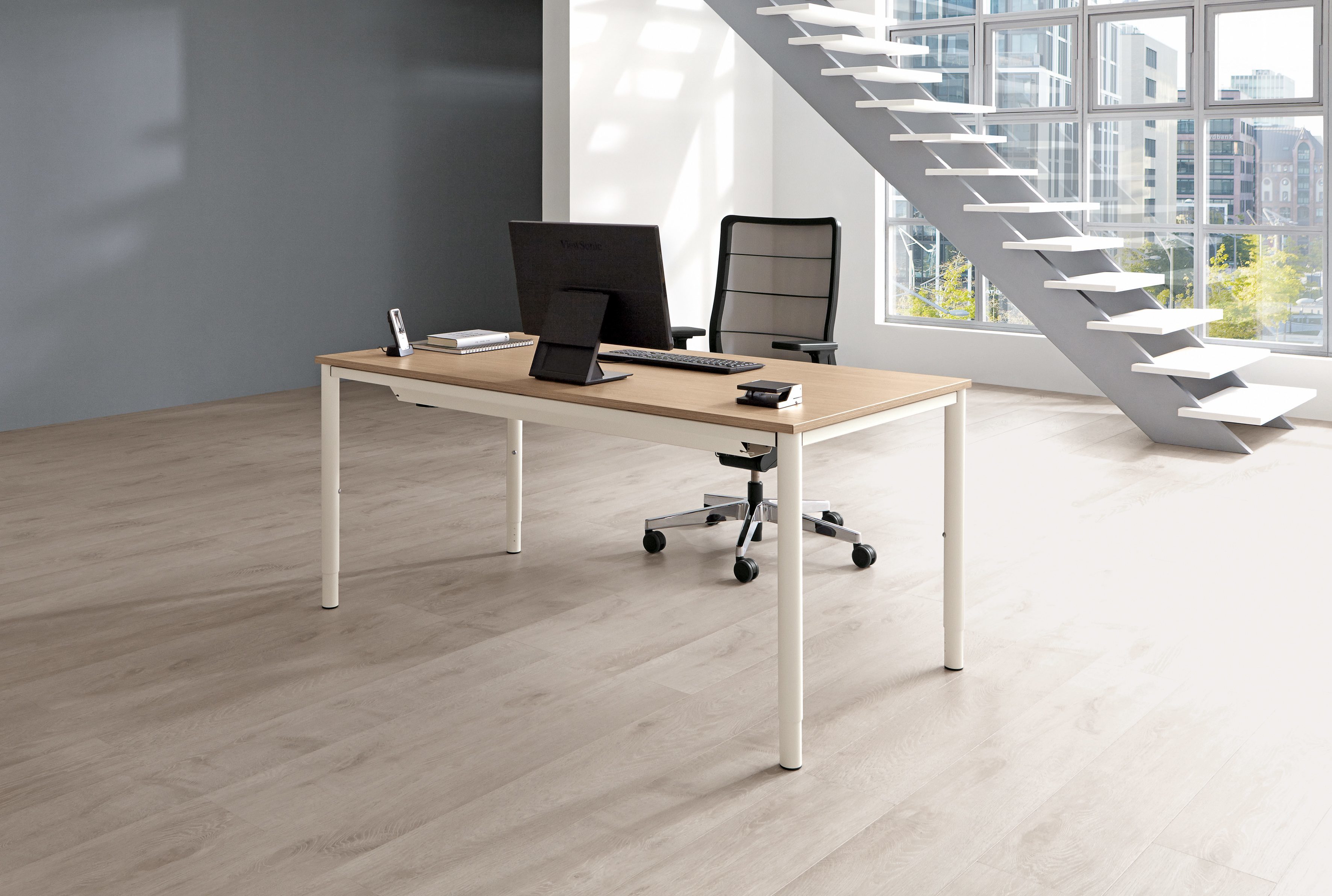 Moderner Palmberg Schreibtisch Sinac, höhenverstellbar, mit Bürostuhl, Monitor und Büromaterial in hellem Büro.