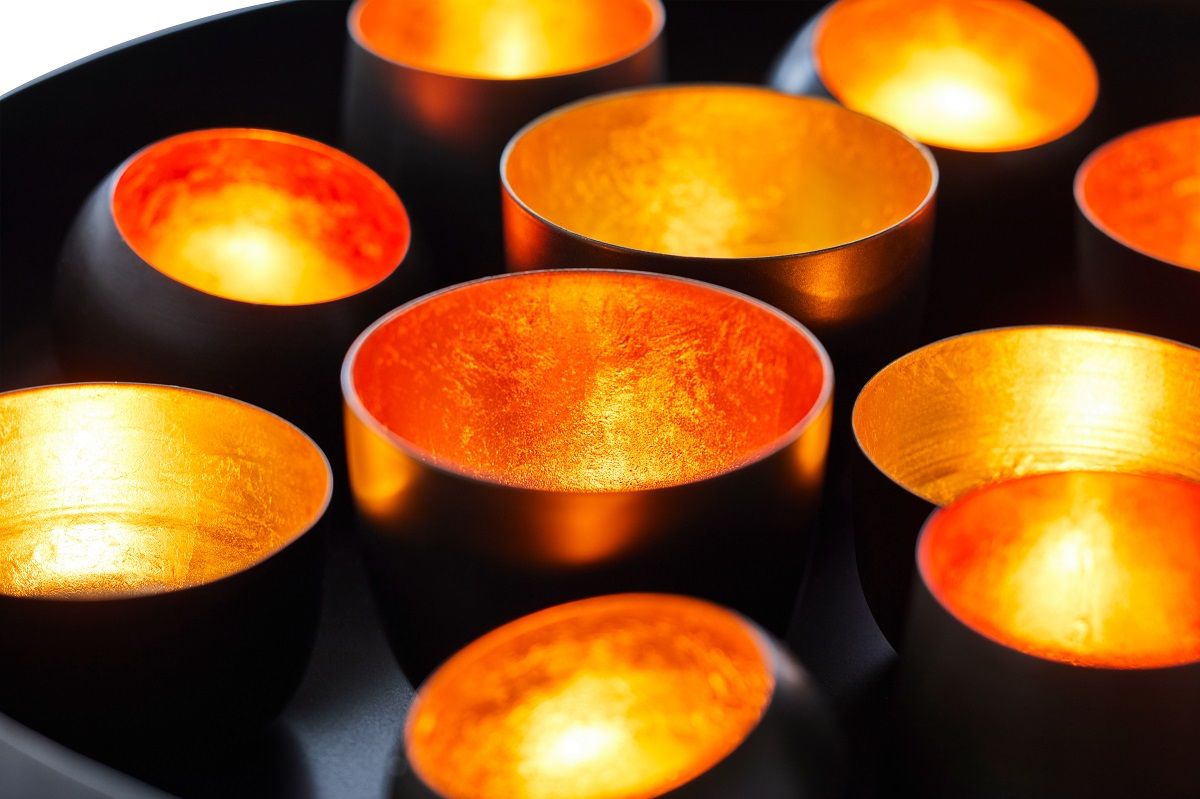 Santa Lucia Tablett: Nahaufnahme von 12 Teelichtern in goldenen Stahlhaltern, stimmungsvolle Beleuchtung.