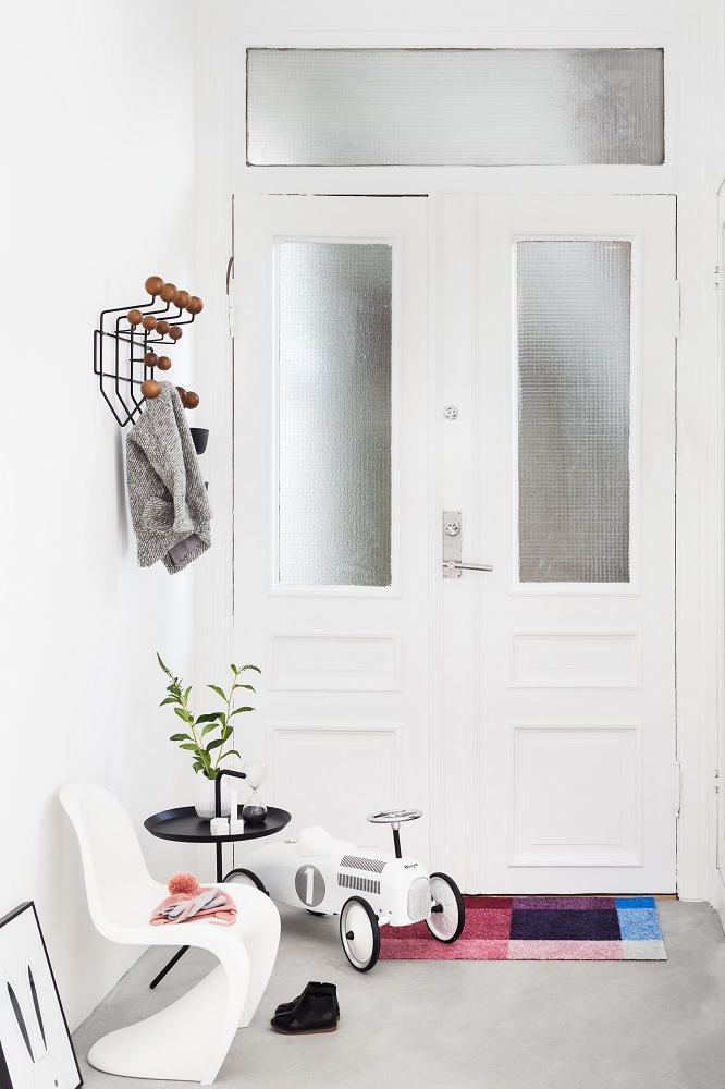 Eingangsbereich mit Heymat Fußmatte in bunten Farben, Kinderspielzeugauto und minimalistischer Einrichtung.