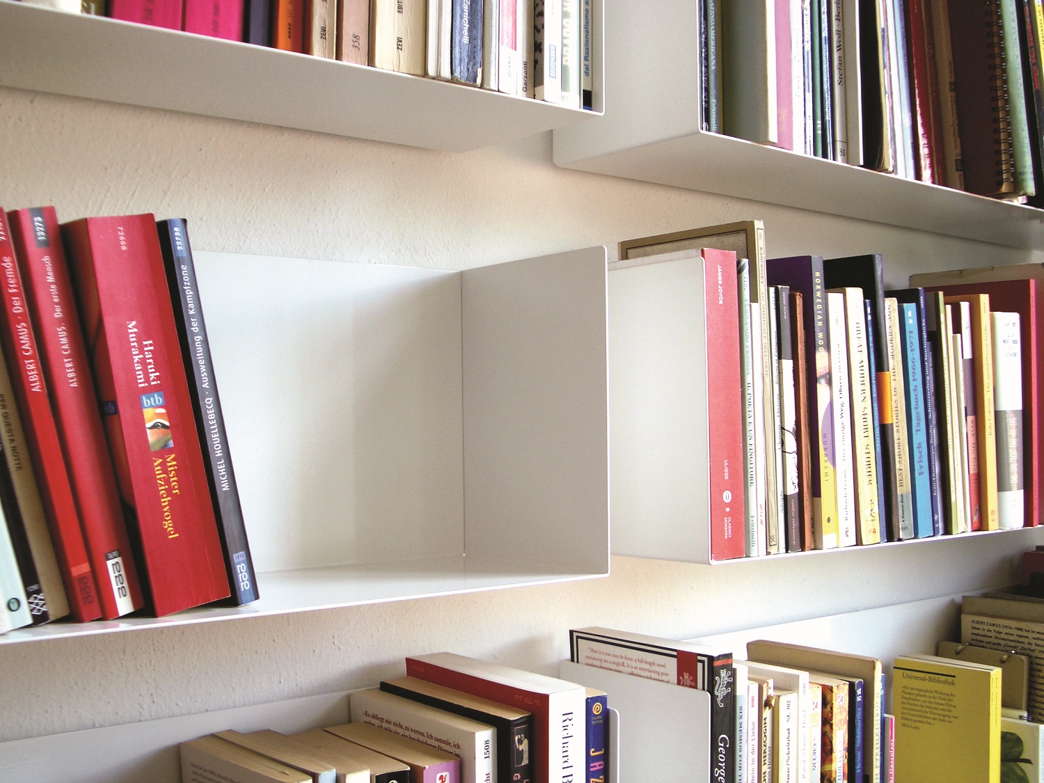 Weißes Taschenbuchregal a Linea1 von Müller Möbelwerkstätten mit Büchern an der Wand befestigt.