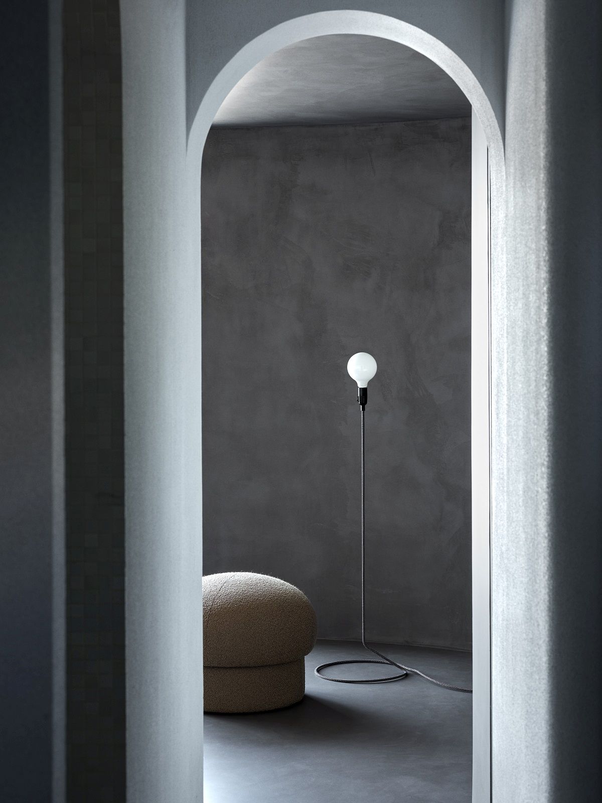 Beiger Uno Pouf Hocker von Design House Stockholm neben einer Stehlampe in minimalistischem Interieur.
