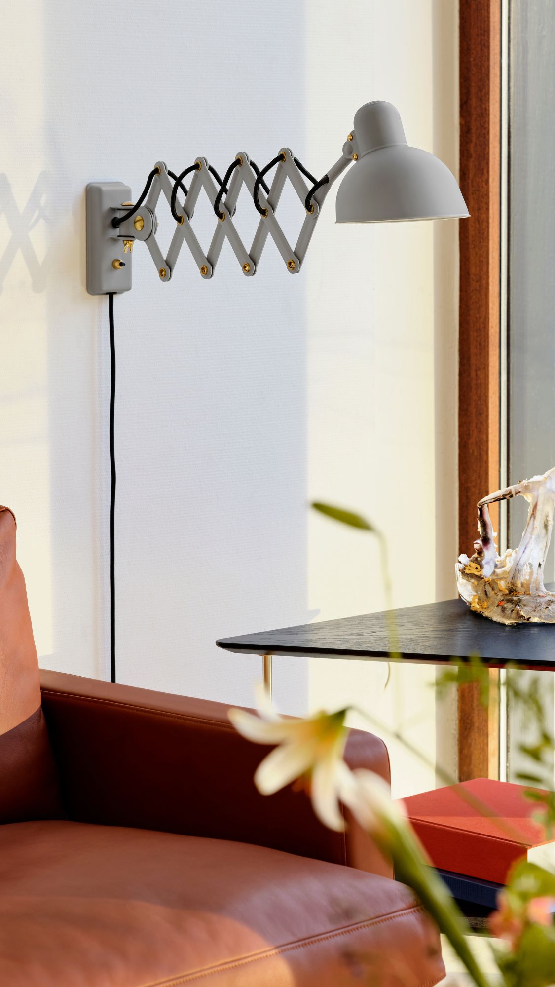 Graue KAISER idell Scherenleuchte 6718 von Fritz Hansen an einer weißen Wand montiert.