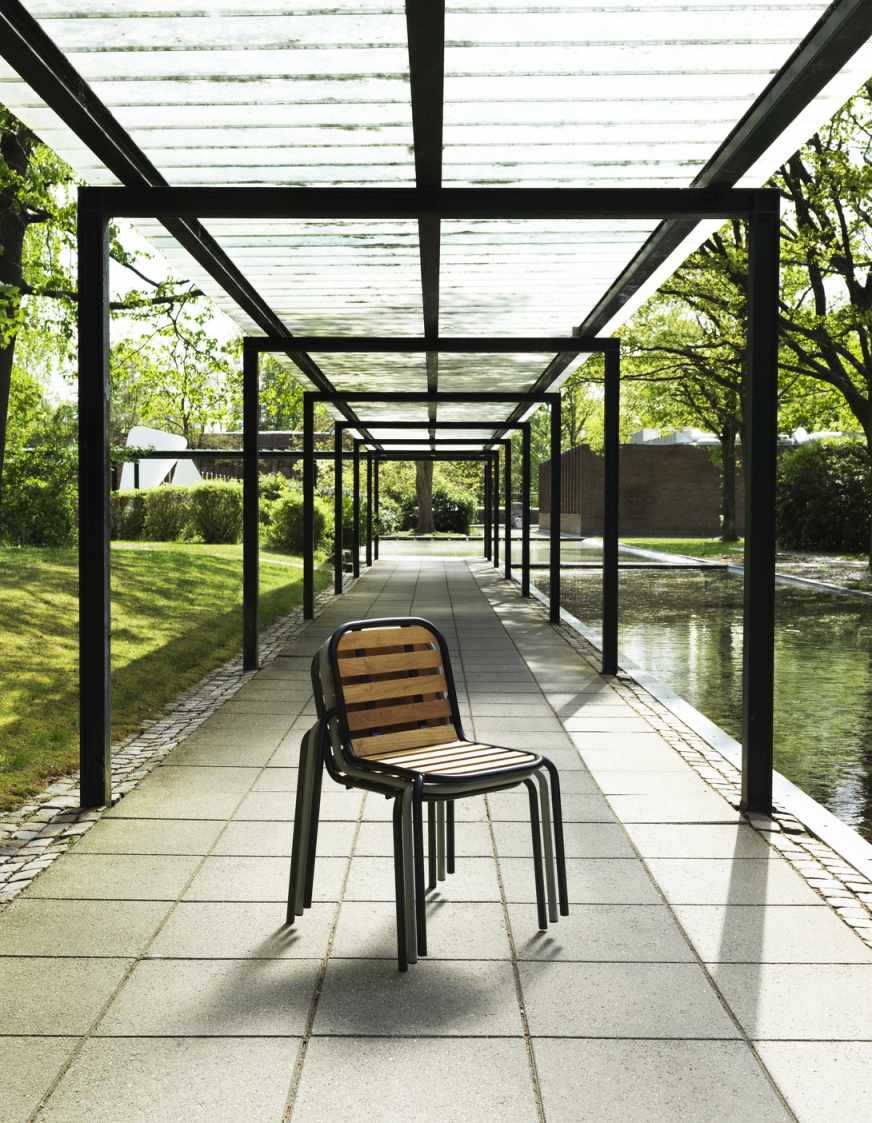Stapelbare Vig Chair Wood Stühle von Normann Copenhagen für den Außenbereich unter einer Pergola.